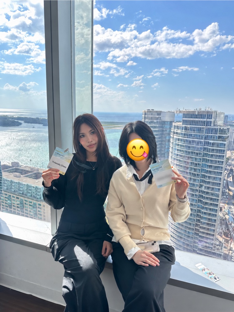 Two people holding event badges beside a waterfront window
