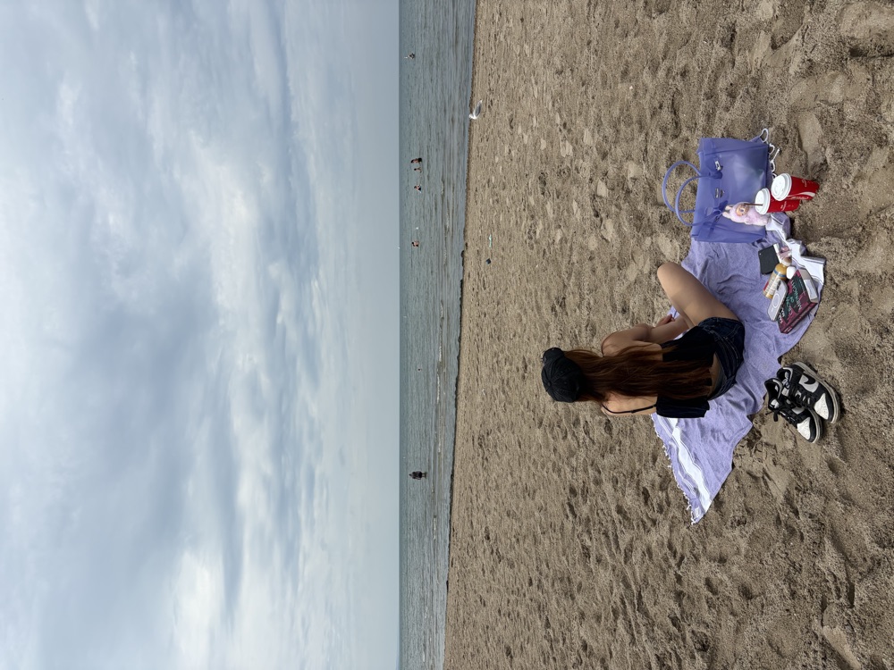 A person sitting on a purple blanket at the beach